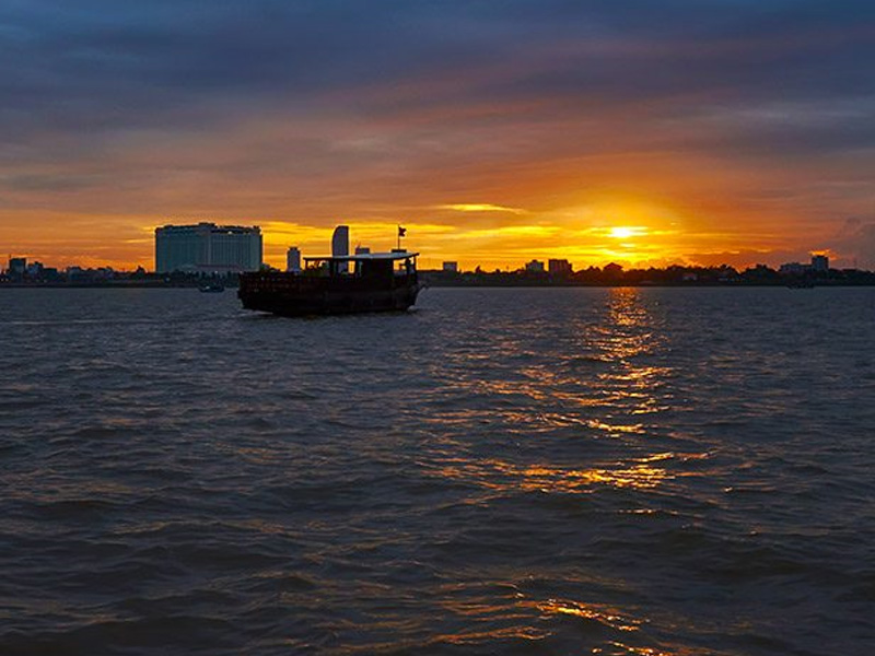 Boat cruising on the Mekong river as the sun sets