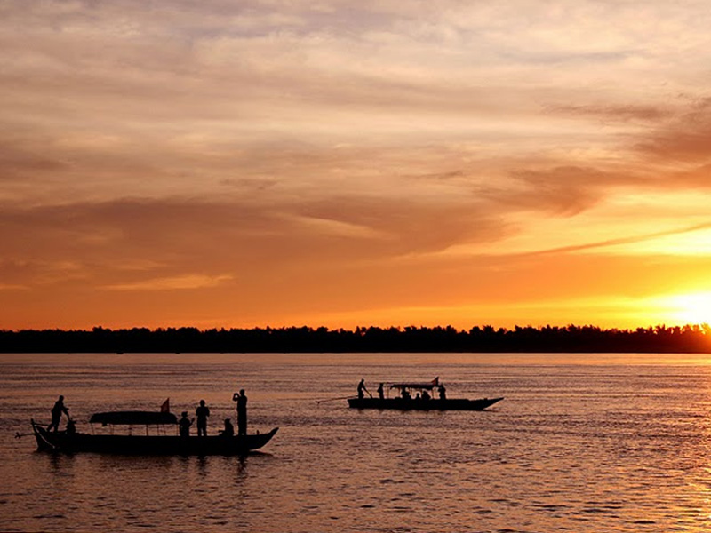 boats on the Mekong River as the sun sets.