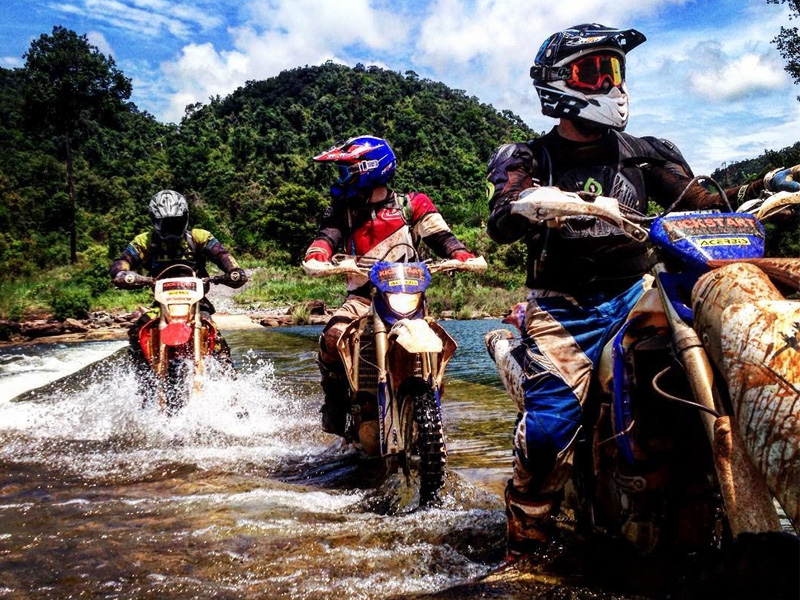 Dirt bikers crossing a river on their dirt bike adventure tour