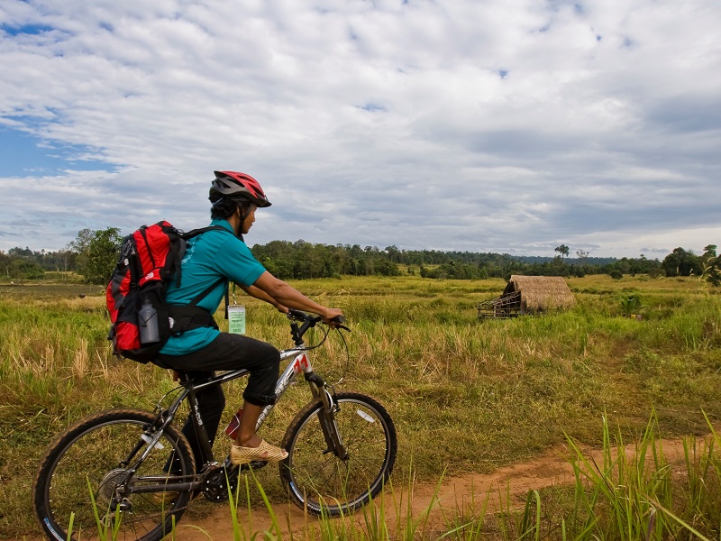 Cambodian man cycling trough the Cambodian countryside