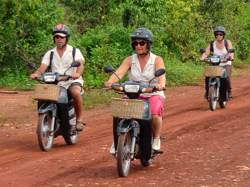 Tourists riding on Honda Dream 125cc motos through the Cambodian countryside