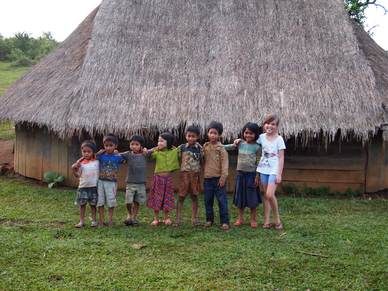 Phnong children posing in front of a traditional hut