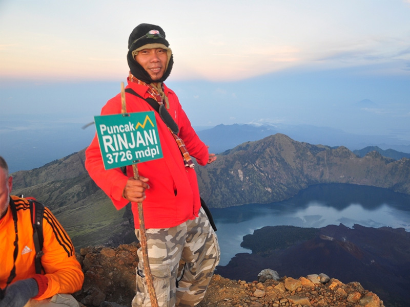 Porter at the top of Mount Rinjani pointing down into the crater