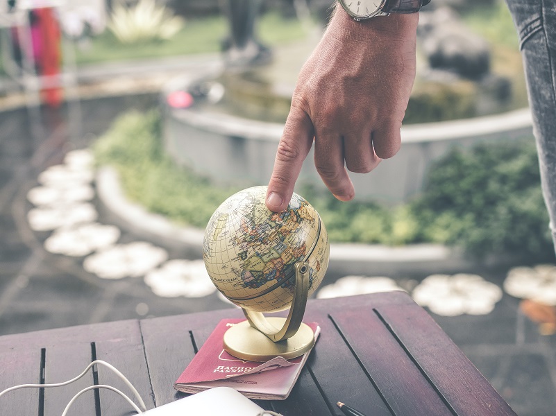 A person touching a small globe figurine.