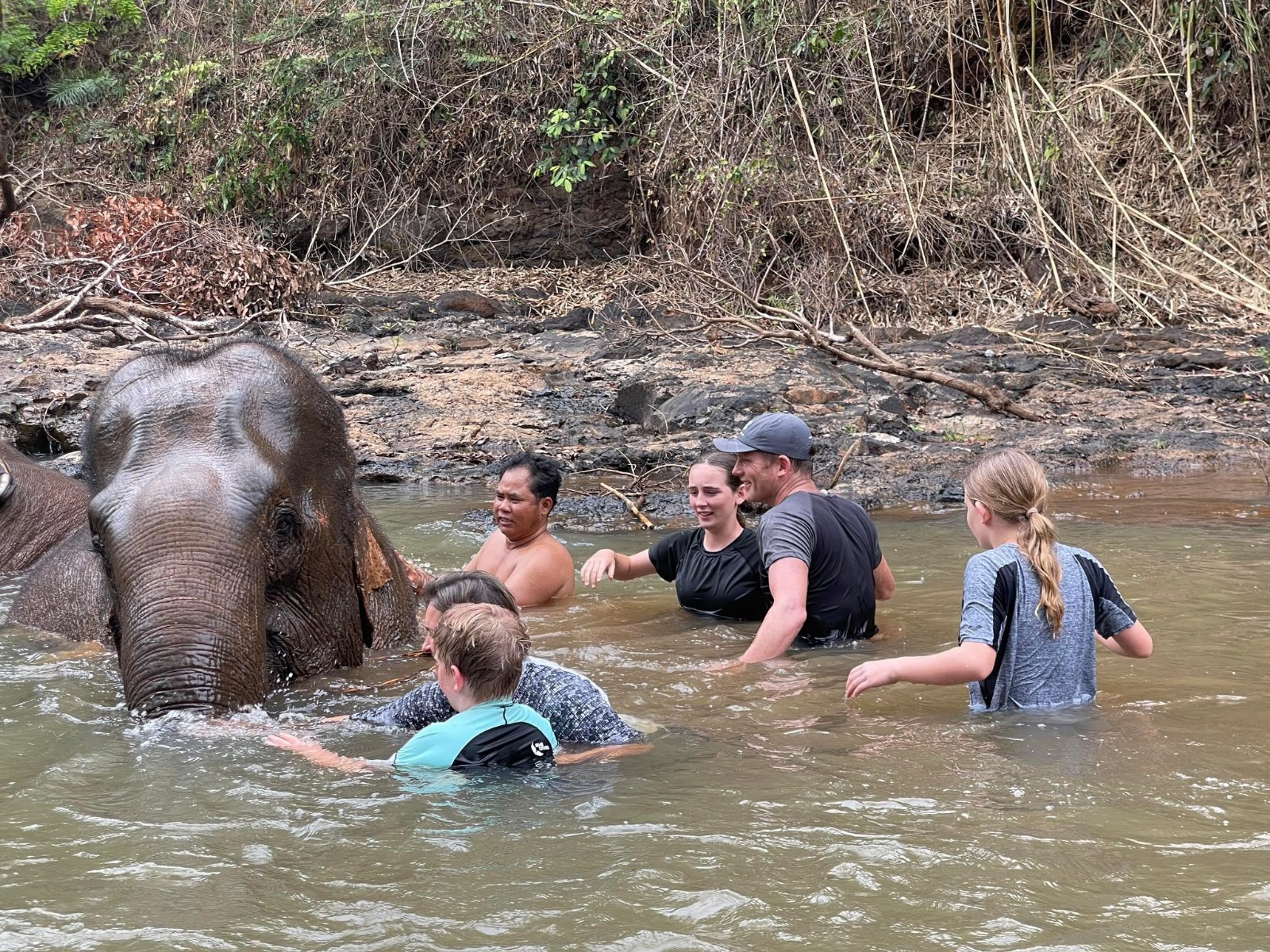 A family on holiday bathing an elephant in Asia